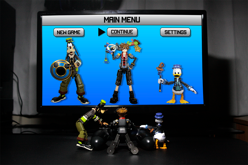  Photo features figures from the Kingdom hearts series. Figures are shown controlling a video game controller together and playing as themselves on a monitor.