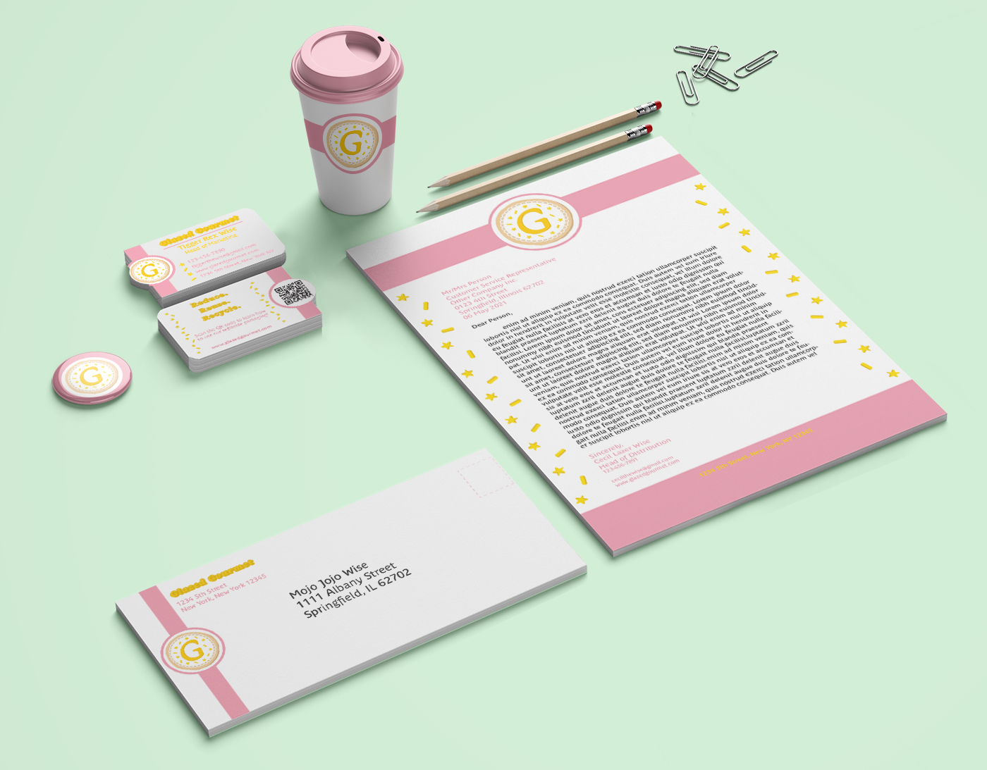 Stationary mockup showing letterhead, envelope, business cards, buttons, and a coffee cup for Glazed Gourmet cookie company.